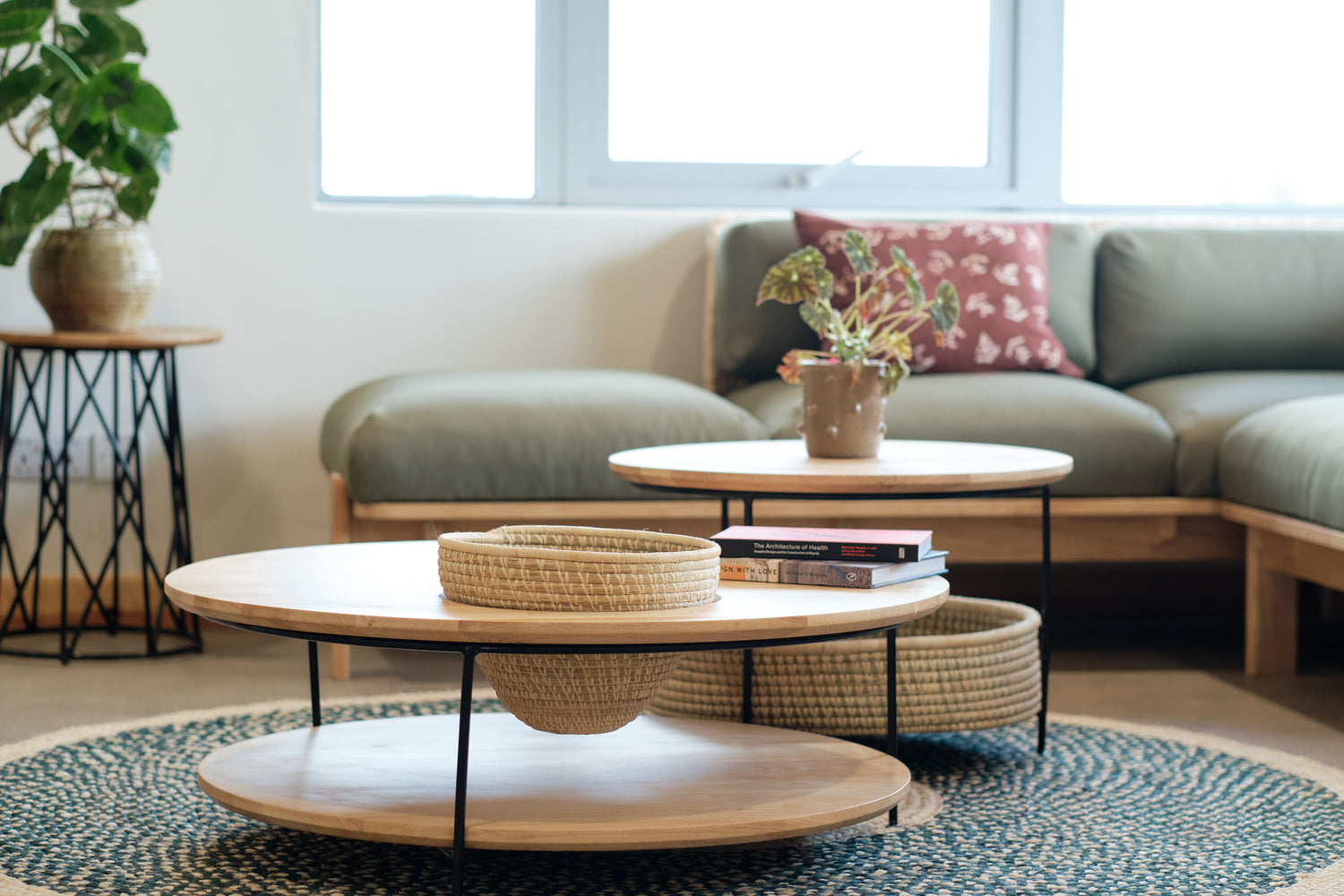 Stylish coffee table with a minimalist wooden top and woven basket storage underneath, paired with a patterned woven rug and modern sectional sofa.